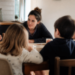 Adulte assis face a plusieurs enfants autour table
