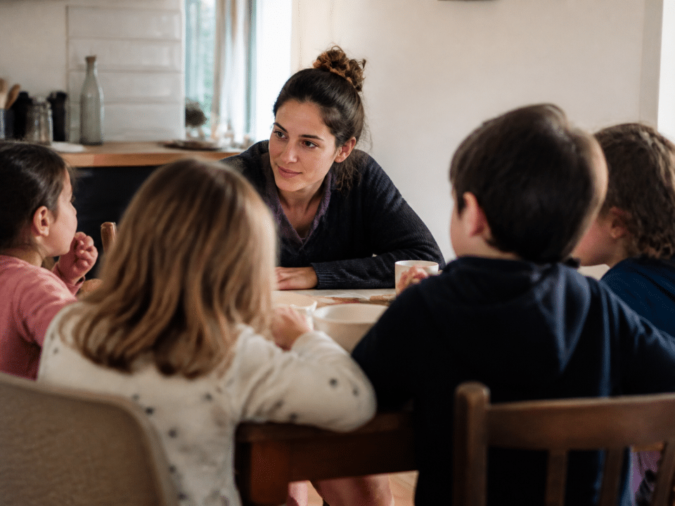 Adulte assis face a plusieurs enfants autour table