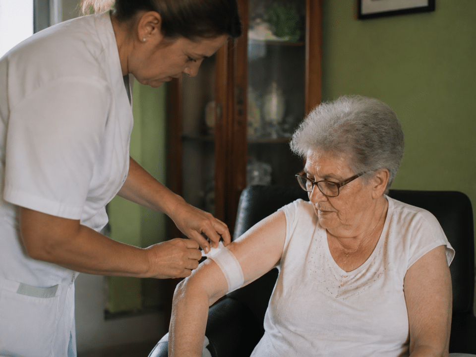 Personne agee assise recevant aide medicale d'un soignant debout