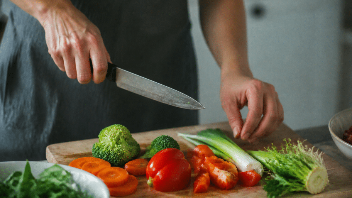 Mains tenant couteau au-dessus planche decoupage avec legumes