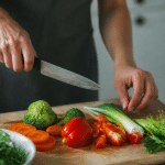 Mains tenant couteau au-dessus planche decoupage avec legumes