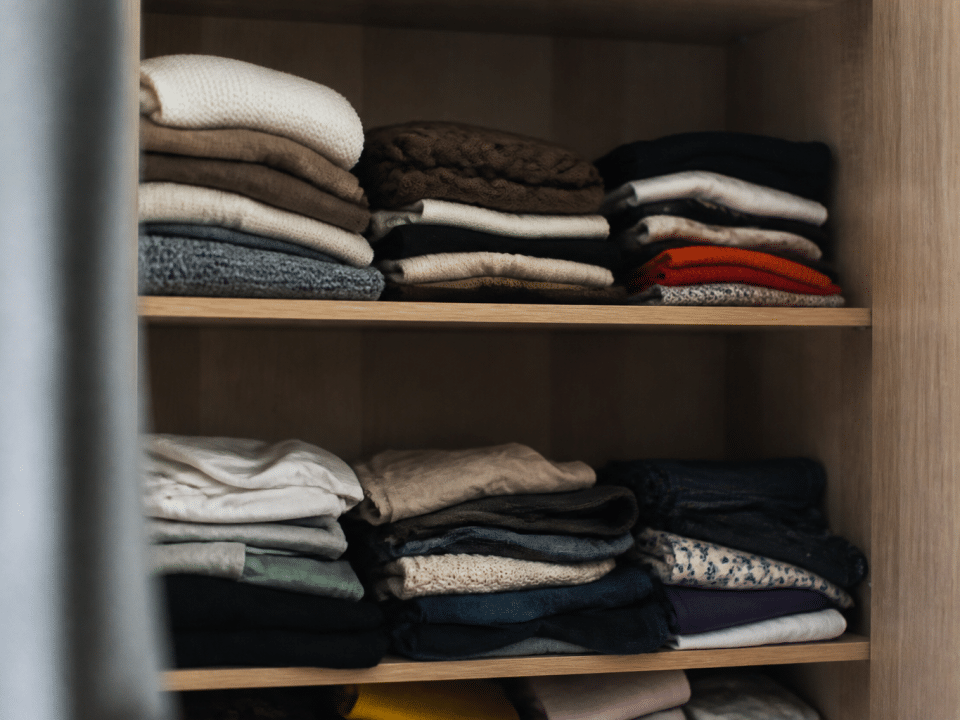 Vetements plies et empiles sur etageres ouvertes d'armoire