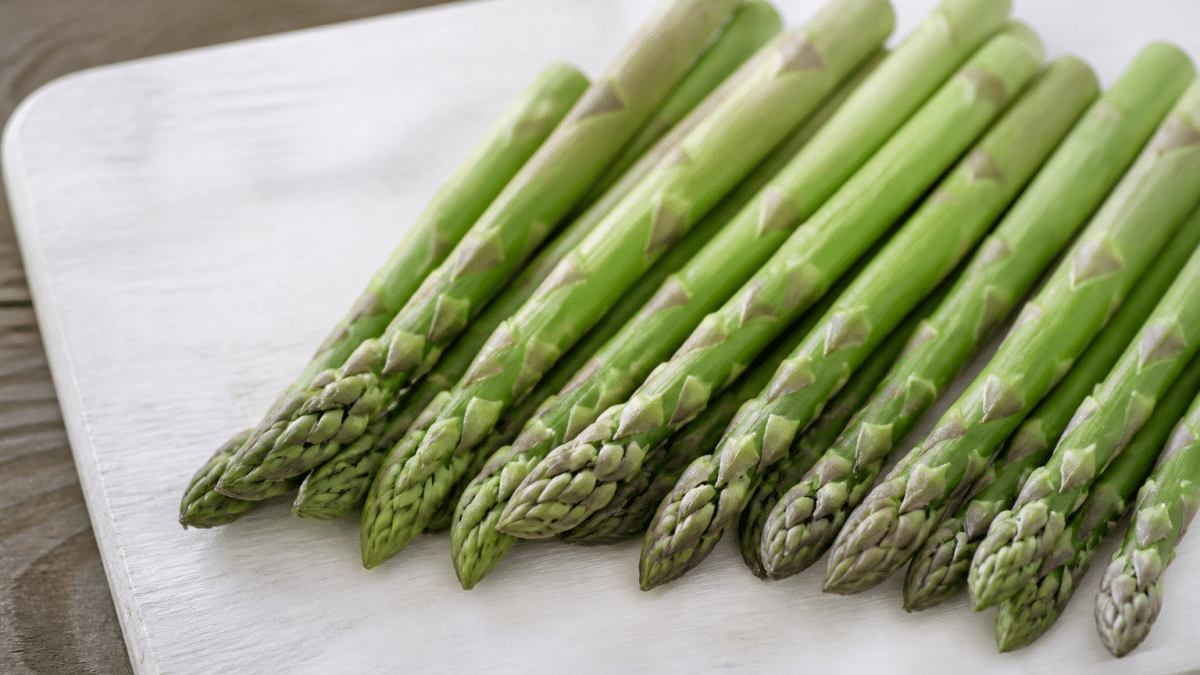 Asperges vertes fraîches alignées sur planche bois blanc