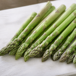 Asperges vertes fraîches alignées sur planche bois blanc