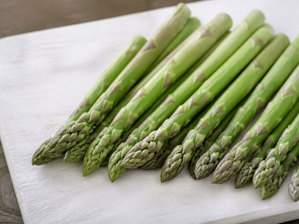 Asperges vertes fraîches alignées sur planche bois blanc
