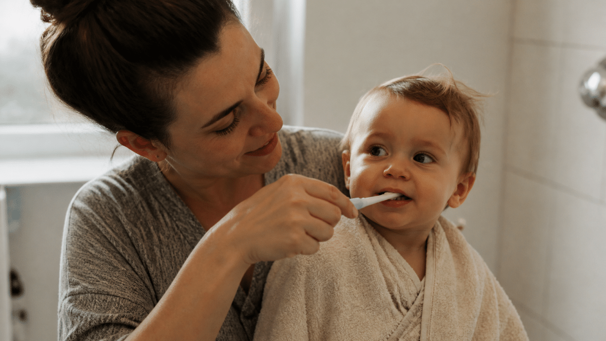Parent tenant bébé sur le cote brossant ses petites dents