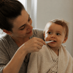 Parent tenant bébé sur le cote brossant ses petites dents