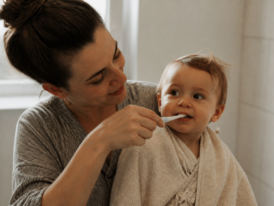 Parent tenant bébé sur le cote brossant ses petites dents