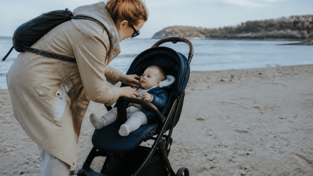 Parent tenant nourrisson assis dans poussette sur plage