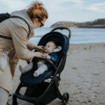 Parent tenant nourrisson assis dans poussette sur plage