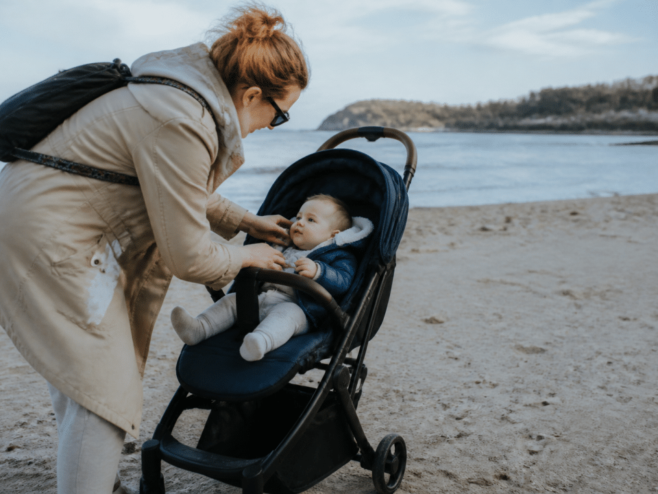 Parent tenant nourrisson assis dans poussette sur plage