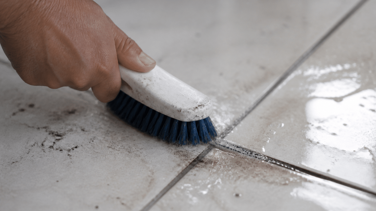 Brosse frottant vigoureusement joint carrelage tache noire épaisse