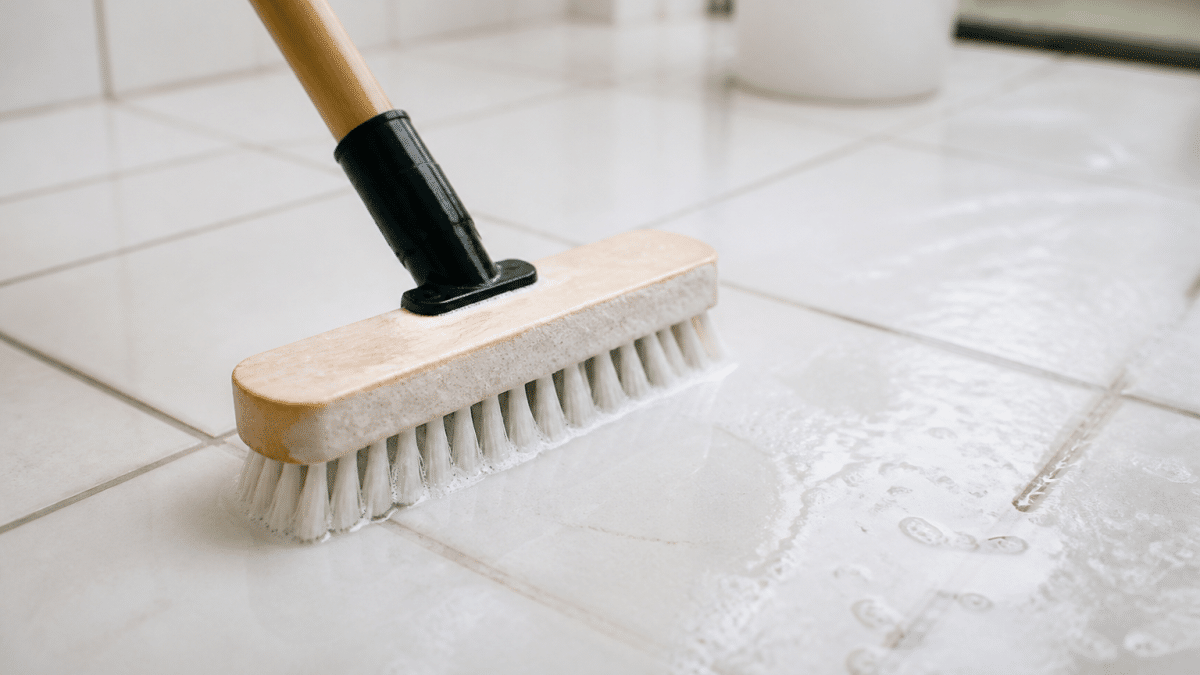 Brosse appliquee sur carrelage blanc avec solution nettoyante