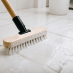 Brosse appliquee sur carrelage blanc avec solution nettoyante