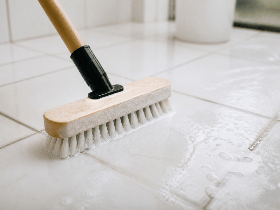 Brosse appliquee sur carrelage blanc avec solution nettoyante