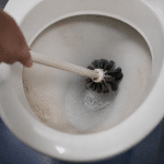 Brosse de toilettes frottant vigoureusement une cuvette blanche encrassee
