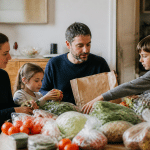 Famille de quatre personnes autour table avec courses alimentaires