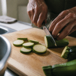 Mains tranchant courgettes vertes sur planche de cuisine bois
