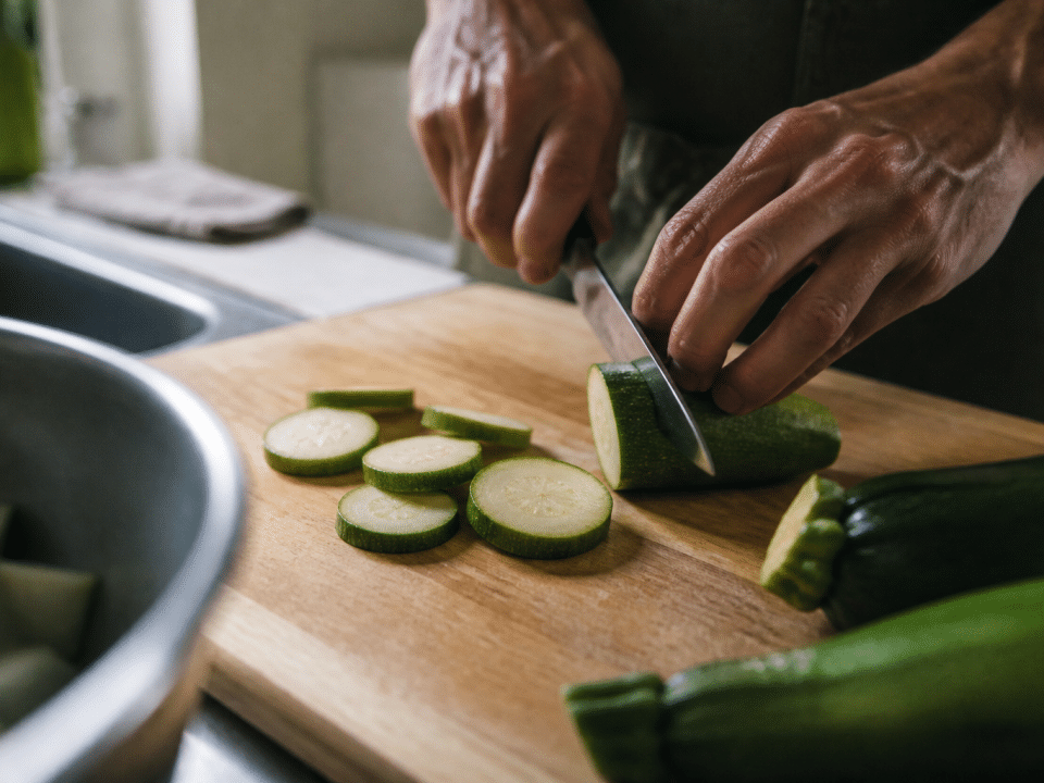 Mains tranchant courgettes vertes sur planche de cuisine bois