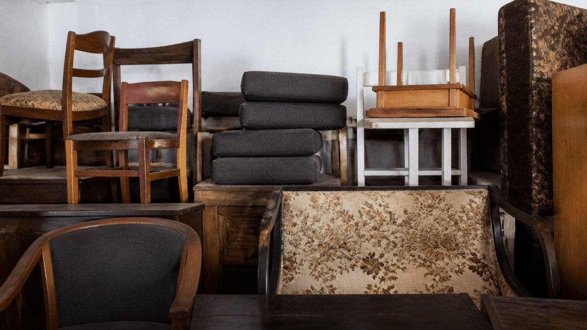 Pieces of furniture stacked high against white wall indoors