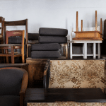Pieces of furniture stacked high against white wall indoors