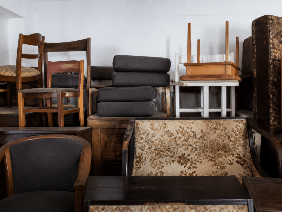 Pieces of furniture stacked high against white wall indoors