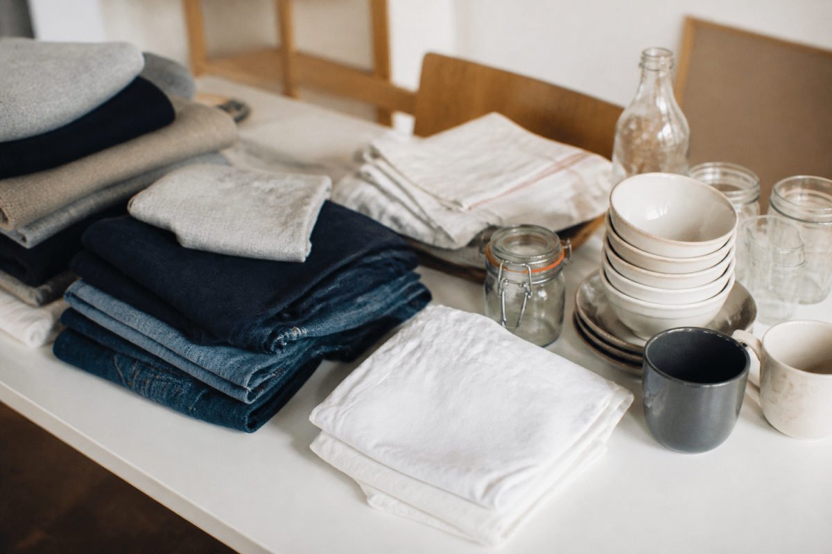 Vetements plies et objets de cuisine tries sur table blanche