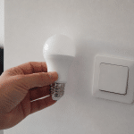 Main tenant ampoule LED pres d'interrupteur eteint