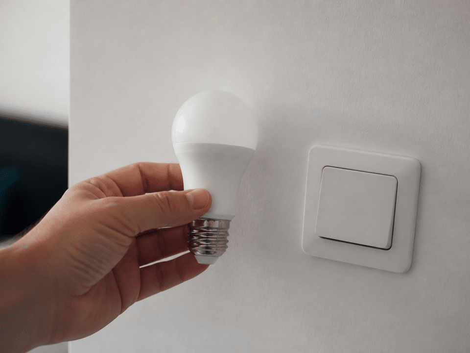 Main tenant ampoule LED pres d'interrupteur eteint