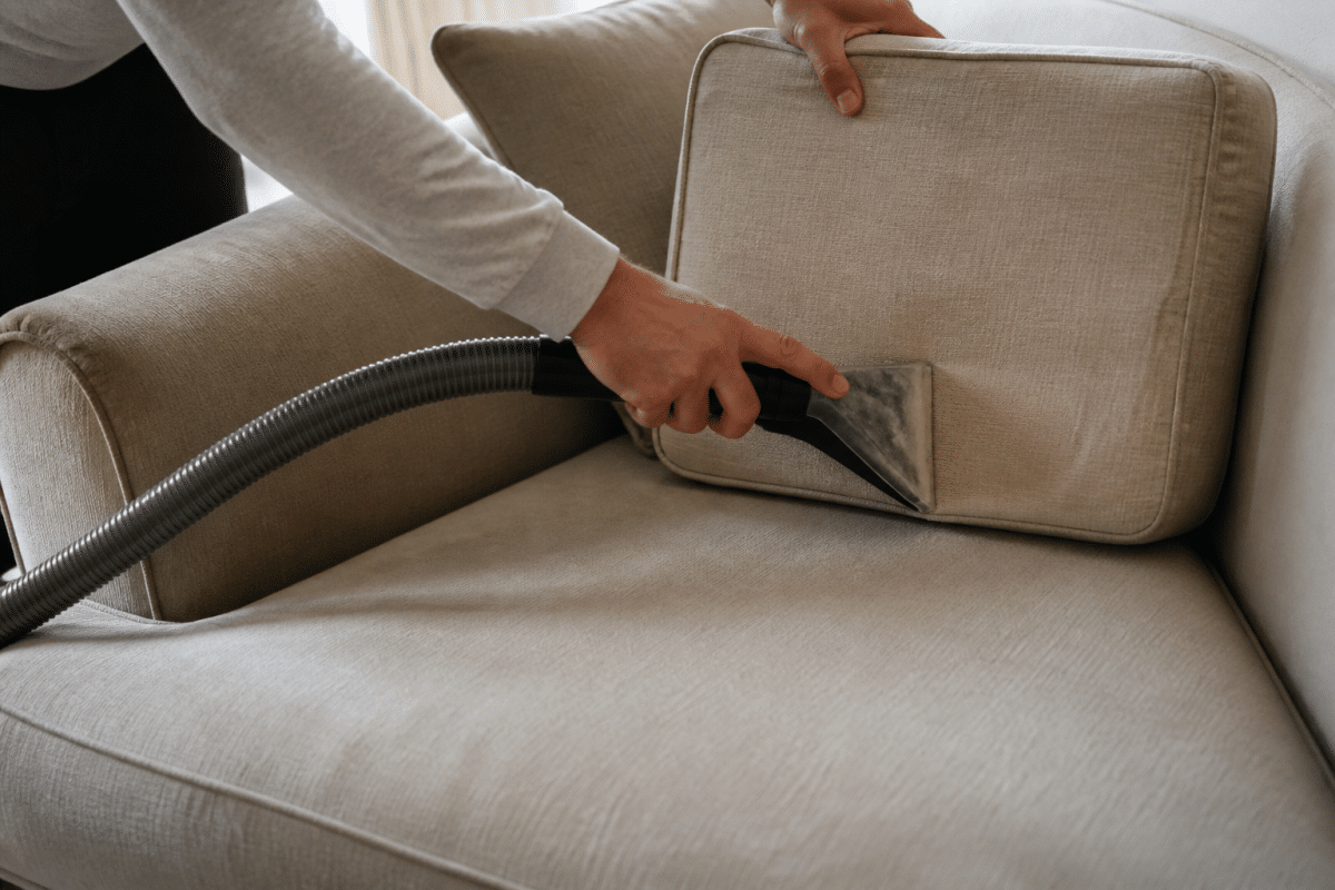 Main aspirant un canape beige avec coussin retourne
