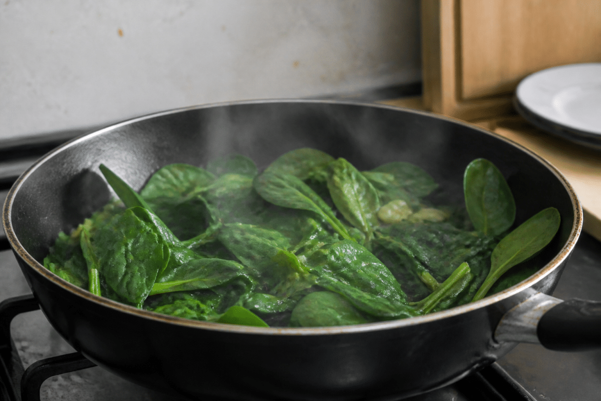 Poêle avec épinards verts frais et vapeur cuisson