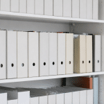 Etageres blanches remplies de boites rangees verticalement alignees