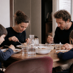 Famille de quatre personnes assise autour table repas