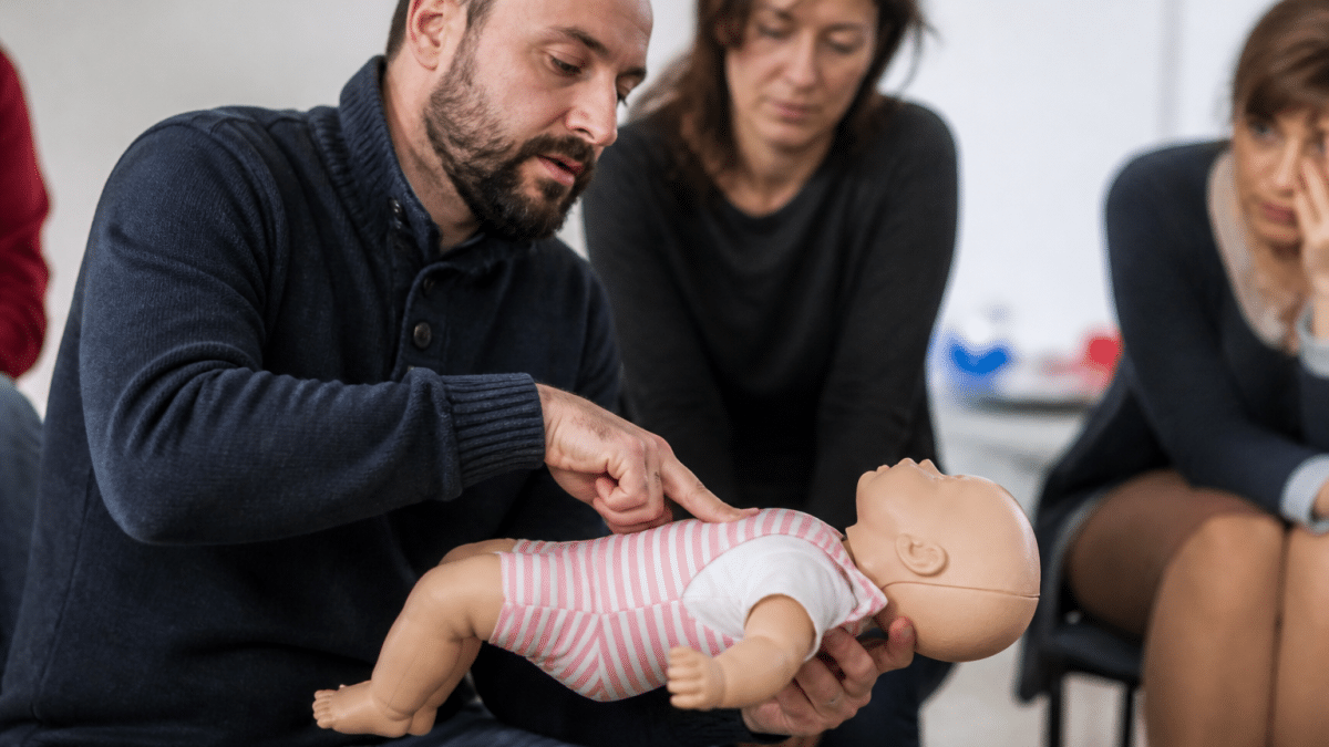 Instructeur montrant techniques réanimation sur mannequin bébé allongé