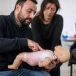 Instructeur montrant techniques réanimation sur mannequin bébé allongé