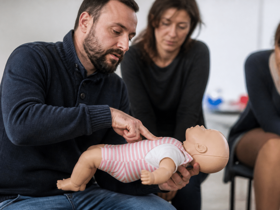 Instructeur montrant techniques réanimation sur mannequin bébé allongé