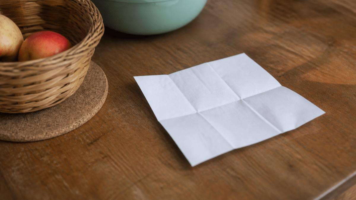 Liste de courses ecrite sur papier posee sur table de cuisine
