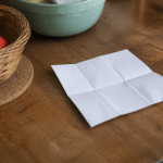 Liste de courses ecrite sur papier posee sur table de cuisine