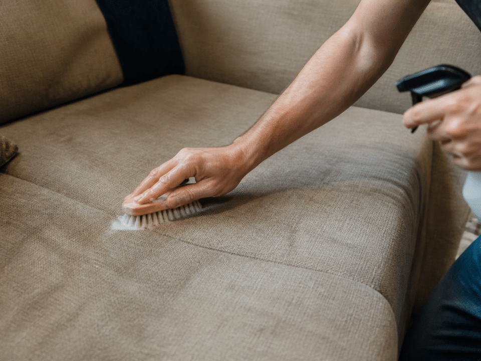 Personne frottant tissu canape avec brosse et produit nettoyant