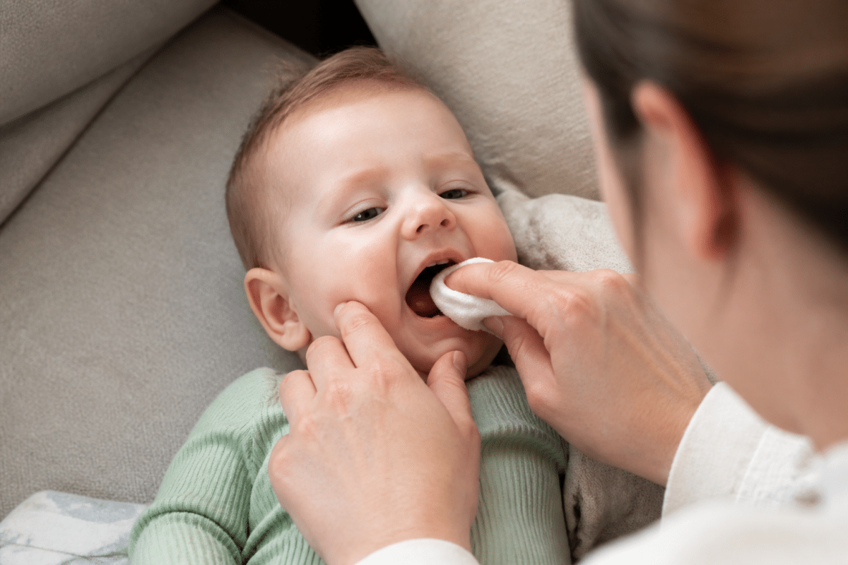 Parent nettoie doucement petites dents bébé avec compresse humide