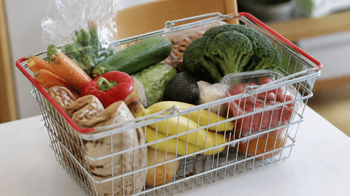 Panier d'epicerie rempli d'articles alimentaires sur table blanche