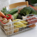 Panier d'epicerie rempli d'articles alimentaires sur table blanche