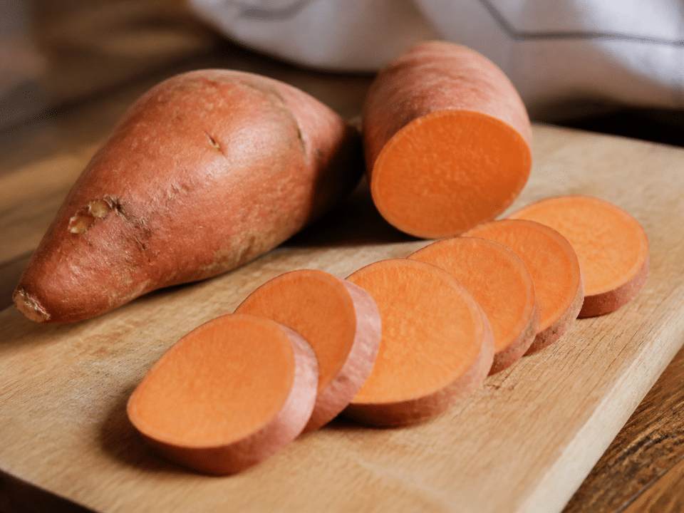 Patate douce entiere et tranchee sur planche bois