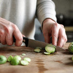 Mains coupant choux de bruxelles frais sur planche bois