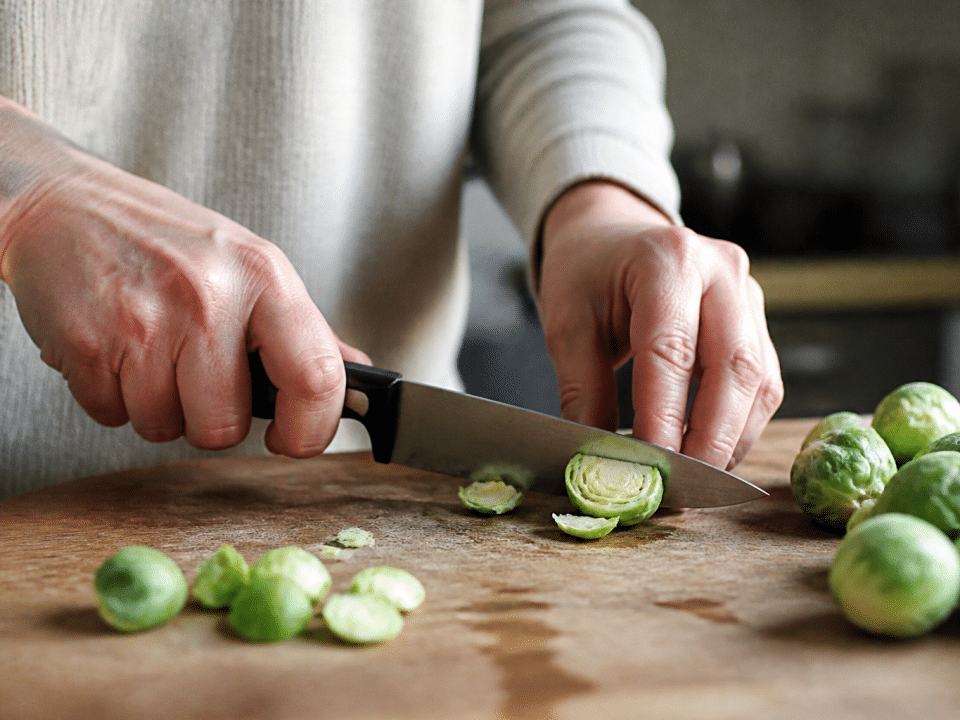 Mains coupant choux de bruxelles frais sur planche bois