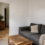 Petit salon aux murs blancs avec meubles simples et accessoires economiques