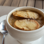 Bol blanc rempli de soupe a l'oignon doree avec croutes flottantes