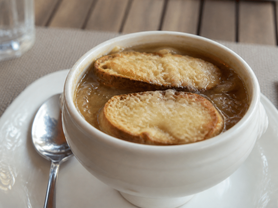 Bol blanc rempli de soupe a l'oignon doree avec croutes flottantes