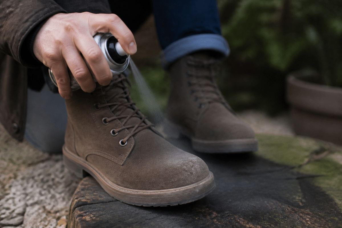 Main vaporisant spray impermeabilisant sur chaussures daim