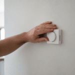Thermostat mural baisse avec main posee dessus geste economie